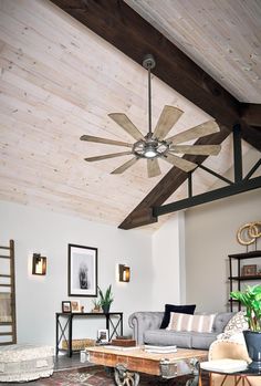 a living room with a couch, table and ceiling fan in the middle of it