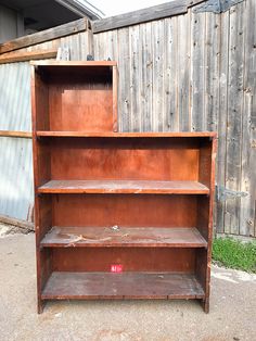 an old wooden bookcase sitting outside in front of a barn door with no doors on it