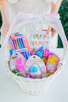 a woman holding a basket filled with lots of different items and greeting cards in it