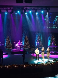 a group of people standing on top of a stage in front of purple and blue lights