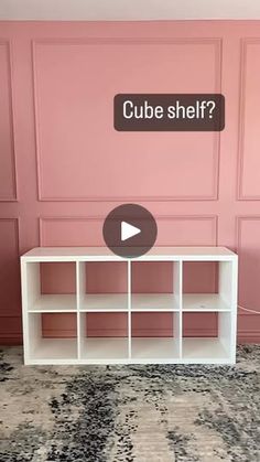 a room with pink walls and a white shelving unit in front of the wall