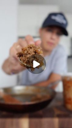 a person holding food in their hand while sitting at a table