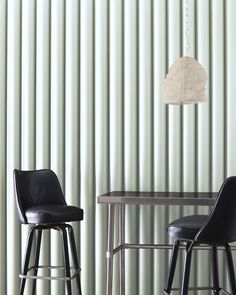 two black leather stools in front of a table with a lamp hanging from the ceiling