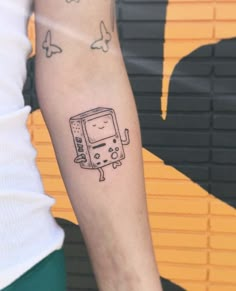 a person with a tattoo on their arm holding a small tv set in front of them