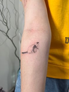 a small mouse tattoo on the left arm