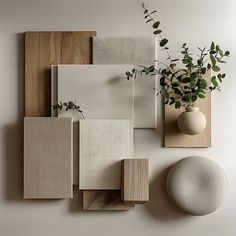 a white vase sitting on top of a wooden shelf next to some tiles and a plant