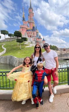 a family poses for a photo in front of the sleeping beauty castle at disneyland world