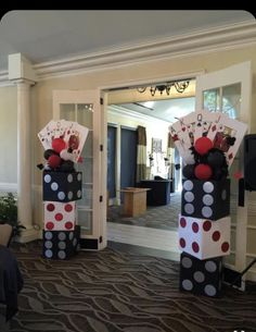 two tall black and white polka dot columns with cards on them in front of a door