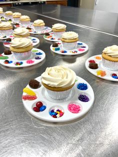 cupcakes are arranged on white plates with colorful icing and sprinkles