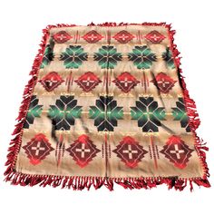 a blanket with red, green and black designs on the bottom is laying on a white surface