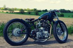 the motorcycle is parked on the side of the road in front of some grass and trees