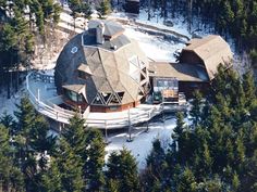 an aerial view of a house surrounded by trees in the snow with lots of snow on the ground