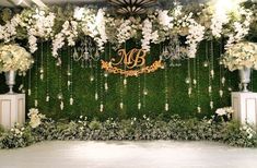 the wedding backdrop is decorated with white flowers and greenery, along with a monogrammed sign