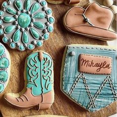 decorated cookies with cowboy boots and name on them sitting on a wooden table next to cookie cutters