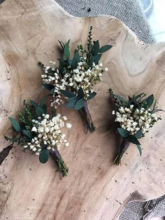 three bouquets of flowers sitting on top of a wooden slab