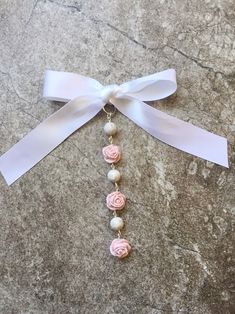 a necklace with pink roses and pearls hanging from it's side on a marble surface