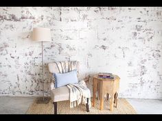 a chair sitting next to a table with a lamp on top of it and a rug in front of it