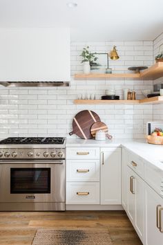 a kitchen with white cabinets and gold trim on the stove top, shelves above it