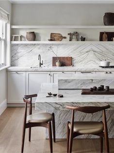 a kitchen with marble counter tops and wooden chairs