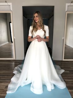 a woman in a white dress is standing on a blue mat with her hands together