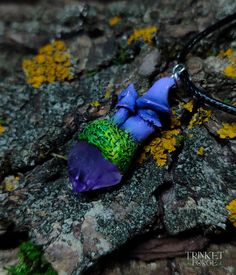 a purple and green piece of glass sitting on top of a stone slab with moss