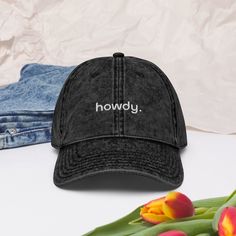 a black hat sitting on top of a table next to tulips and jeans