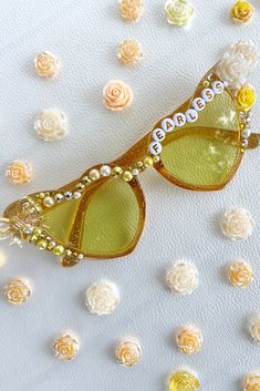 a pair of sunglasses sitting on top of a white surface with flowers around it and the words happy written on them