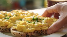 someone is picking up scrambled eggs on a toasted bread