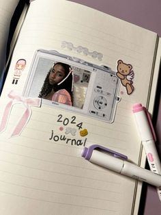 an open notebook with pictures and writing on the page next to it is a pen, two markers, and a teddy bear