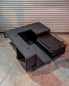 an office desk made out of two briefcases on top of each other, in front of a garage door