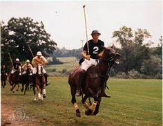 two polo players on horses with their backs turned to the opposite direction as they race each other