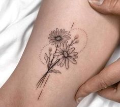 a woman's arm with daisies tattoo on it