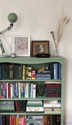 a bookshelf filled with lots of books next to a lamp and pictures on the wall