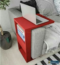 a red side table with a laptop on it in the middle of a living room