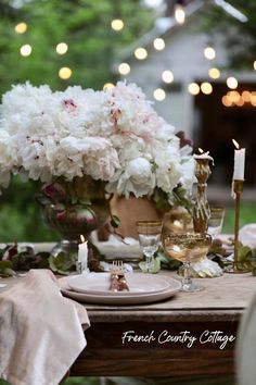 the table is set with white flowers and candles for an elegant dinner or party setting