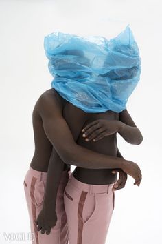 two black people hugging each other with a plastic bag on their head