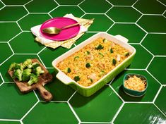 a casserole dish with broccoli and cheese in it on a green tile floor