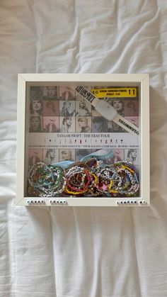 a white box with many different bracelets in it on top of a bed next to a pen