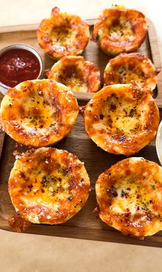 several mini pizzas on a wooden tray with dipping sauce