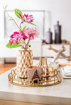 a vase with pink flowers sitting on top of a table next to other decorations and books