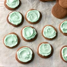 some cookies with green frosting are on a piece of paper next to other cookies