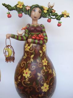 a ceramic figurine is standing next to a vase with flowers and fruit on it