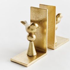 two gold bookends that are shaped like birds and one has a bird on it's head