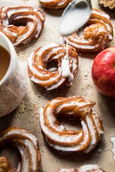 apple cider donuts with cinnamon glaze and an apple next to them on a baking sheet