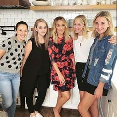 four women standing in a kitchen posing for the camera