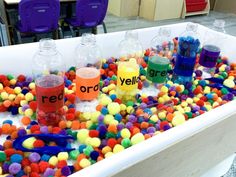 there are many different colored balls in the bathtub with water and plastic letters on it