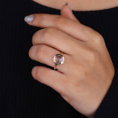 a woman's hand wearing a ring with an oval shaped stone in the middle