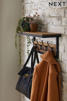 a coat rack with two coats hanging on it next to a potted plant and purse