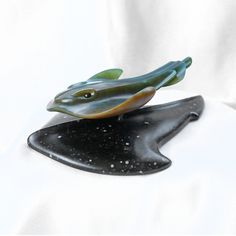 a glass figurine of a fish sitting on top of a piece of black marble