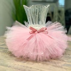 a pink tutu skirted vase sitting on top of a wooden table